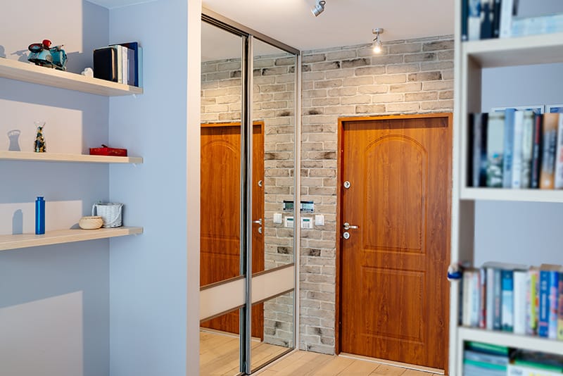 Szafa na wymiar w zabudowie wnęki to jedno z najpopularniejszych rozwiązań. Drzwi służą także za lustro, co pozwala oszczędzić miejsce na innej ścianie.